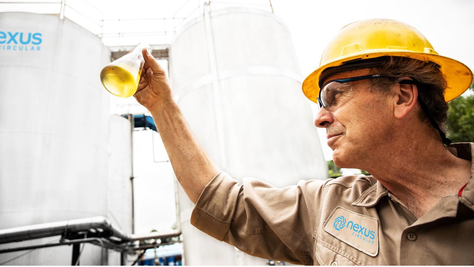 a man holding a beaker with a yellow liquid in it